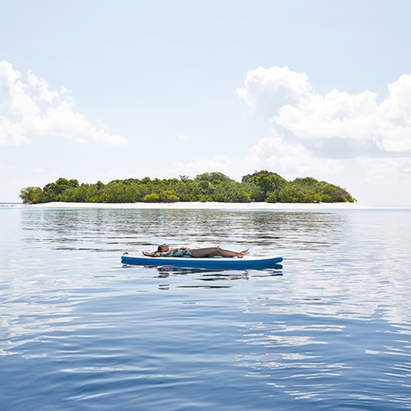 Kvinde ligger på padlleboard på Conrad Rangali Maldiverne